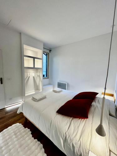 une chambre avec un grand lit blanc avec des oreillers rouges dans l'établissement Appartement moderne climatisé centre-ville, à Avignon