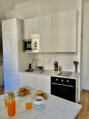 une cuisine équipée d'une table avec des assiettes de nourriture et du jus d'orange dans l'établissement Appartement moderne climatisé centre-ville, à Avignon