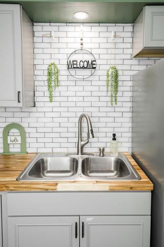 a kitchen with a stainless steel sink and white tiles at Meadow View BNB in Lima