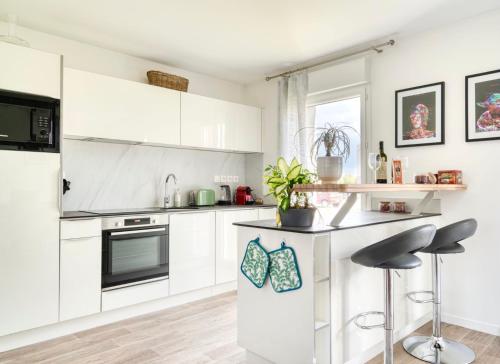 une cuisine avec des armoires blanches et un comptoir avec des tabourets dans l'établissement Maison élégante entre Caen & mer, à Cambes-en-Plaine
