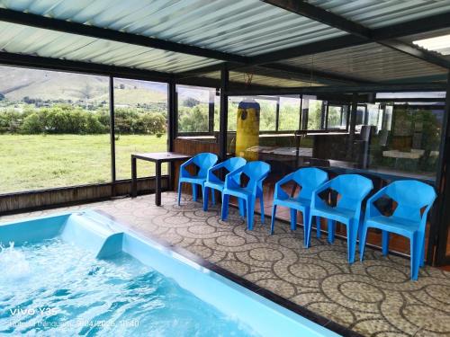 a pool with blue chairs and a table and a bar at Hotel San Luis Sachica ng in Sáchica