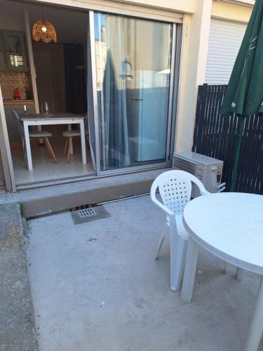 a patio with a table and a table and chairs at Appartement proche des thermes in Balaruc-les-Bains