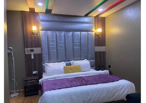 a bedroom with a large bed with a large headboard at Grand Diamond Hotels & Suites LTD in Owerri