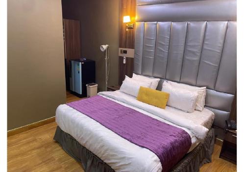 a bedroom with a large bed with two yellow pillows at Grand Diamond Hotels & Suites LTD in Owerri