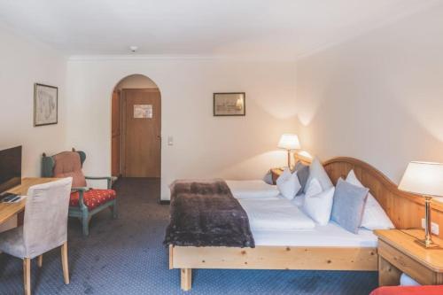 a hotel room with a large bed and a desk at Kertess in Sankt Anton am Arlberg