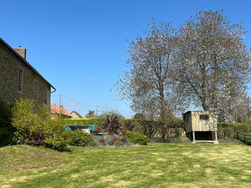 a yard with a bird house in the grass at Maison des H, au bord de l'Etang in Canisy