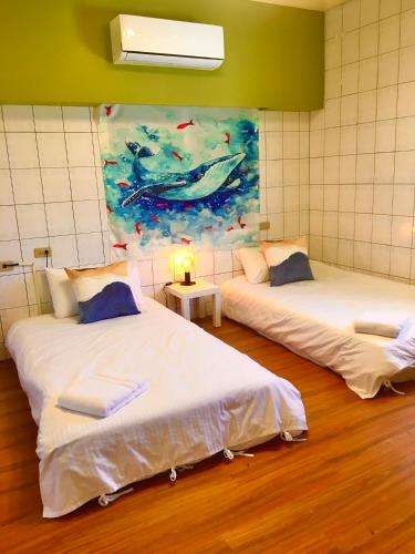 two beds in a room with a painting on the wall at Liuqiu Cozy Room in Xiaoliuqiu