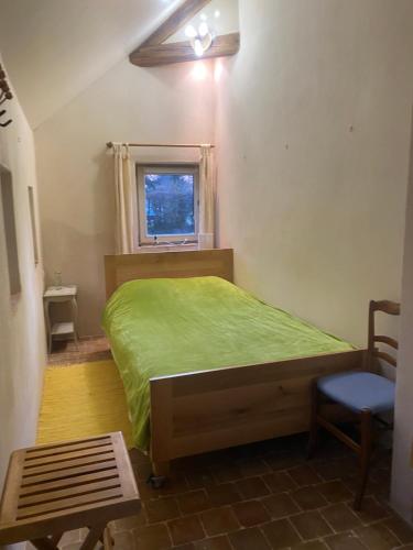 une chambre avec un lit vert et une fenêtre dans l'établissement Moulin de Boiscorde, au Centre du Perche, à Rémalard