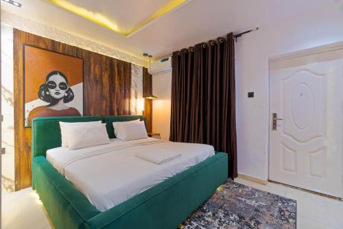 a bedroom with a green bed with a painting on the wall at one bedroom Lekki in Araromi