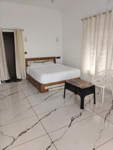 a bedroom with a bed and a table and a chair at Robin's Paradise Deluxe Villa in Vagamon