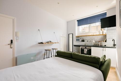 a bedroom with a green couch and a kitchen at Leicester Square Studios in London