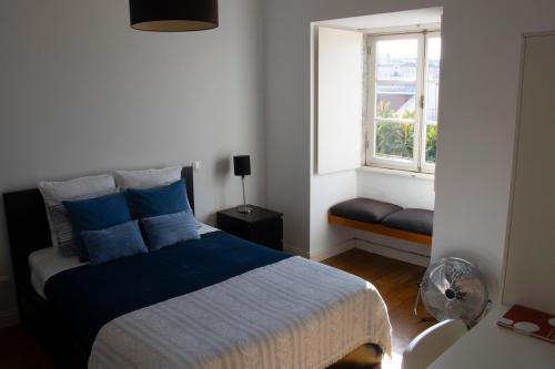 a bedroom with a bed with blue pillows and a window at Joia da Mouraria in Lisbon