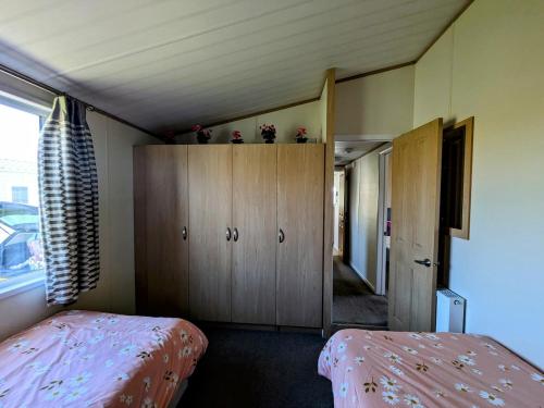 a bedroom with a bed and a cabinet with flowers on it at Dune Haven Luxury Beachside Lodge in Lossiemouth