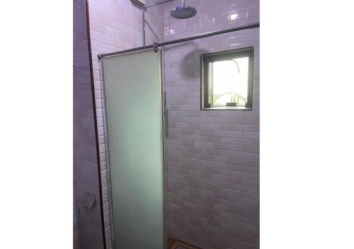 a shower with a glass door next to a brick wall at Grand Diamond Hotels & Suites LTD in Owerri