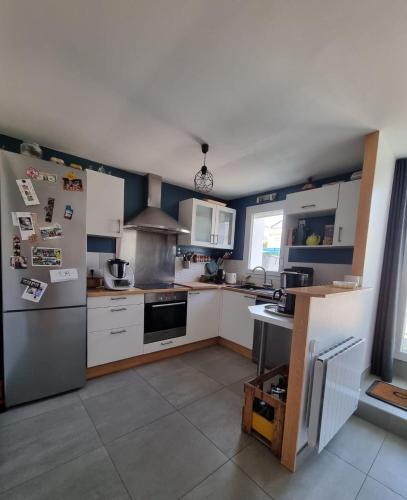  La cuisine est équipée de placards blancs et d'un réfrigérateur. dans l'établissement maison indépendante, à Orvault