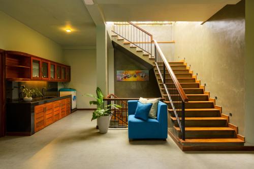 a living room with a staircase and a blue chair at Villa Rumassala Luxury Chalets Unawatuna in Unawatuna