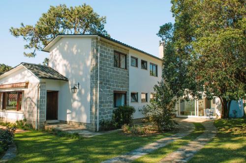 a white house with a tree in the yard at Just Like Home - Casa das Dunas in Moledo