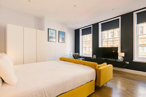 a bedroom with a yellow bed and windows at Leicester Square Studios in London