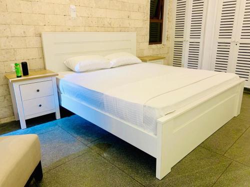 a large white bed in a room with a night stand at Englishpoint Marina Villa in Mombasa
