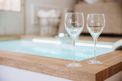 two wine glasses sitting on a table next to a swimming pool at Camilla Luxury Home in Nemi