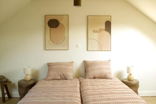 a bed in a bedroom with two pictures on the wall at Maison Magnifiek in Hasselt