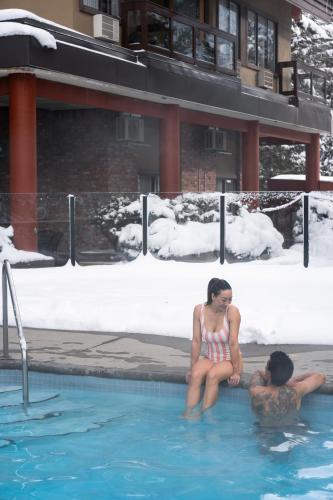 a man and a woman sitting in a swimming pool at Whistler Village Inn & Suites in Whistler