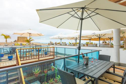 a table with an umbrella on the balcony of a resort at Cotillo Jolanda in Cotillo