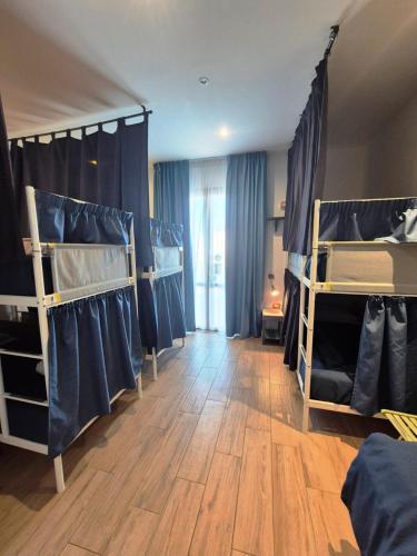 a room with three bunk beds and a wooden floor at Timbuktu Hostel in San Vito lo Capo