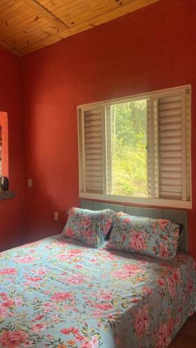 a bed in a bedroom with a window and a bedspread at CHALÉS MARICOTA in Vargem Bonita