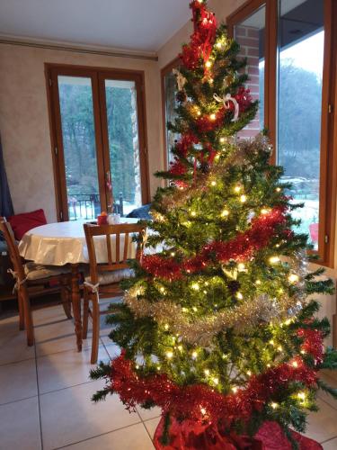 un arbre de Noël dans un salon avec une table dans l'établissement Le chant des hiboux, à Haraucourt