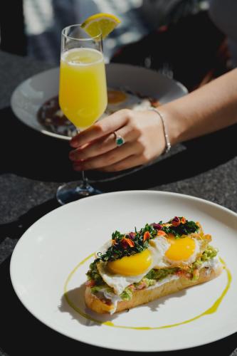 une assiette avec un sandwich aux œufs et un verre de jus d'orange dans l'établissement Quinto Hotel Boutique, à Guaymas