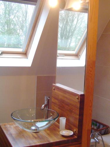 La salle de bains est pourvue d'un lavabo en verre devant un miroir. dans l'établissement Au jet de pierre, à Saint-Inglevert