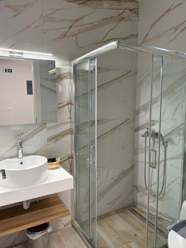 a bathroom with a glass shower and a sink at RoomElioti Apartments in Ofrínion