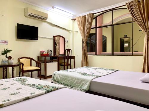 a hotel room with two beds and a window at Hung Vuong Hotel in Ben Tre