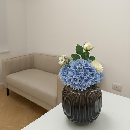 a vase with blue flowers on a table in a living room at AR Palace Hotel - Palermo in Isola delle Femmine
