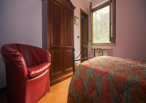 a bedroom with a bed and a chair and a window at I Tre Tigli - Casa di campagna in Rutino