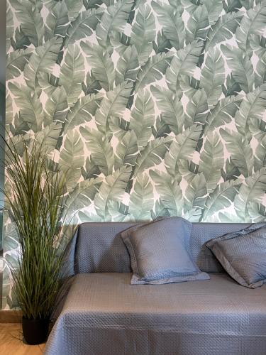 a couch in front of a wall with a leafy wallpaper at Cal Xesc in Castellar de NʼHug