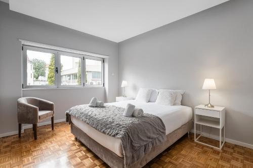 a bedroom with a bed and a chair and a window at GuestReady - Charming City Escape in Braga