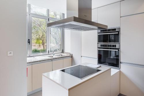 a white kitchen with a sink and a stove at GuestReady - Charming City Escape in Braga