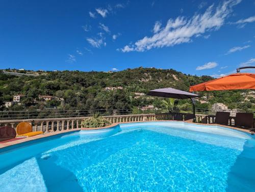 - une piscine avec un parasol et une montagne dans l'établissement Maison niçoise, jardin, piscine, parking double, à Nice