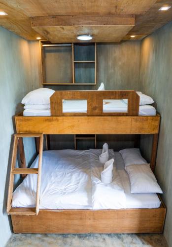 a bunk bed with white sheets and pillows on it at Ohayo Siargao in General Luna