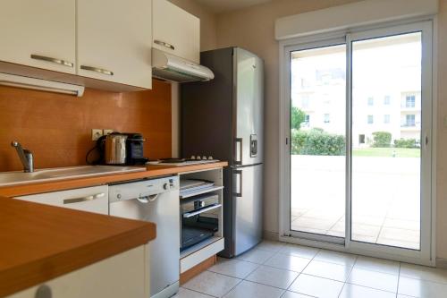 une cuisine avec un réfrigérateur et une porte coulissante en verre dans l'établissement Appartement face village Vendée Globe - 6 personnes, à Les Sables-dʼOlonne