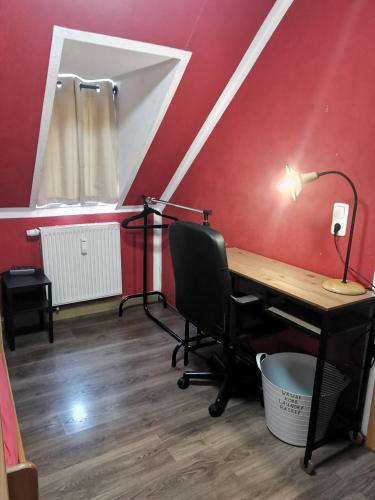 an office with a desk and a lamp on a red wall at SaxonyBNB in Waldheim