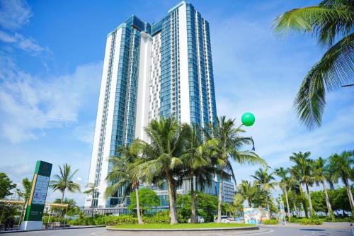 a tall building with palm trees and a green balloon at A La Carte Ha Long Oceanview Fireworksview 2BR2WC suite with balcony in Ha Long