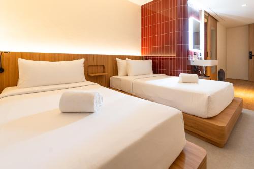 two beds in a hotel room with white sheets at VELA be Bangkok Siam in Bangkok