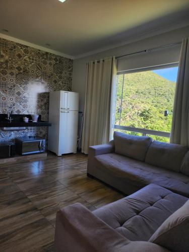 ein Wohnzimmer mit Couch und Kühlschrank in der Unterkunft Rancho paraíso verde in Capitólio