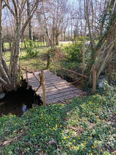 a wooden bridge over a creek in a park at Chambres d hôtes du Moulin de Boiscorde in Rémalard en Perche