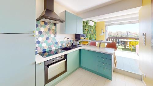 La cuisine est équipée de placards bleus et d'un réfrigérateur. dans l'établissement Villa Bellevue Port Nature3 Village Naturiste 2 chambres, au Cap d'Agde