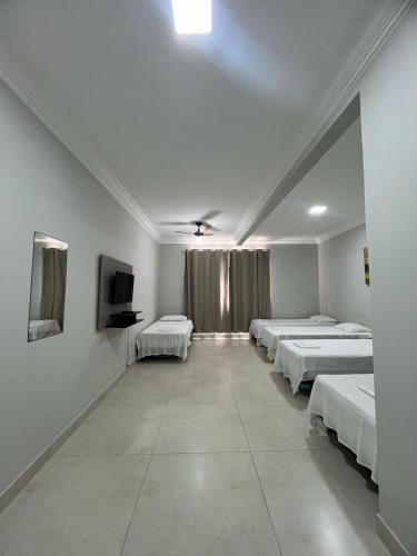 a room with a row of beds and a tv at Apartamento 101 - Suíte ampla para grupos e empresas in Patos de Minas