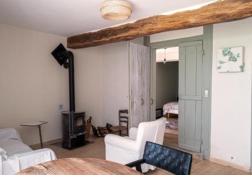 un salon avec un poêle à bois et des chaises blanches dans l'établissement La serre, à Bard-lès-Époisses